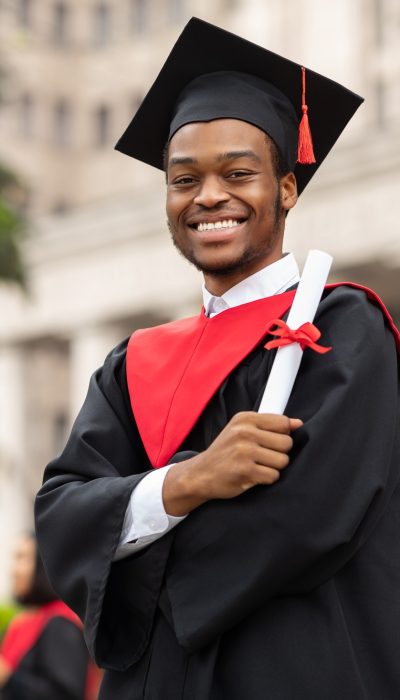 Cheerful african american guy in graduation costume
