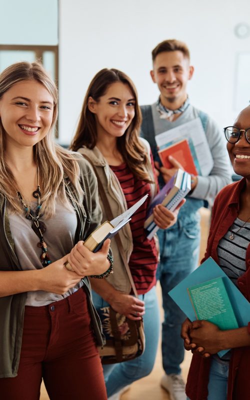 Multi-ethnic group of university students in lecture hall looking at camera.